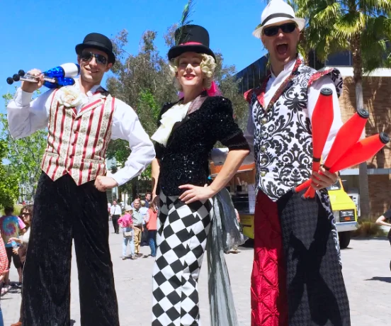 A group of costumed party entertainers, including stilt walkers, posing for live shows and events.